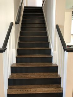 a set of stairs leading up to the second floor in a home with white walls and black railings