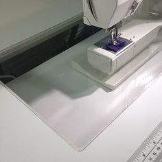 a white sewing machine sitting on top of a table next to a ruler and scissors