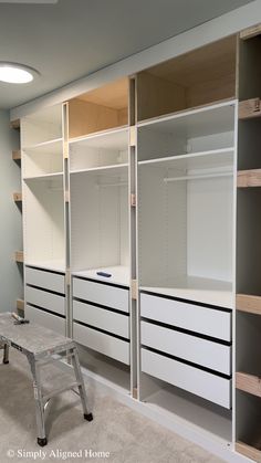 an empty walk - in closet with white drawers and shelving units on the wall