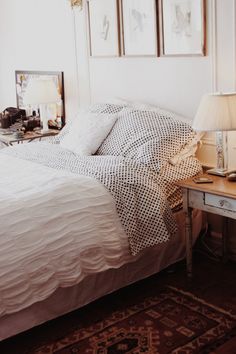 a bedroom with a bed, lamp and pictures on the wall