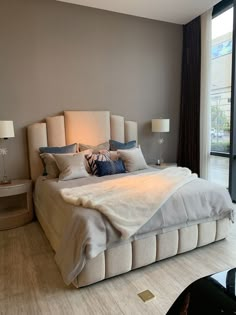 a large bed sitting in the middle of a bedroom next to a tall glass window