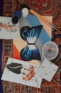 an assortment of art work displayed on top of a table with cloths and other items