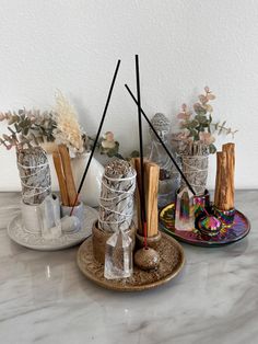 three decorative items are sitting on a table with flowers in vases and candlesticks