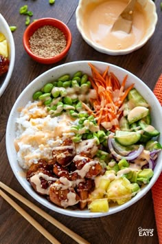 a bowl filled with rice, meat and vegetables next to chopsticks on a table