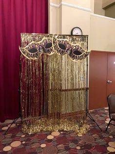 a gold curtain is set up in the middle of a carpeted area with chairs