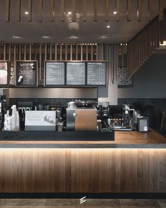 a coffee shop with menus on the wall and wooden counter top, along with two espresso machines