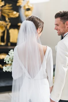 the bride and groom are looking at each other in front of a gold urn