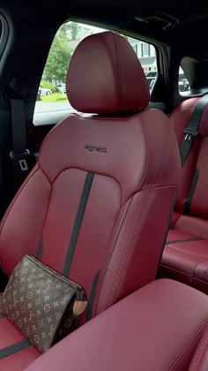 the interior of a car with red leather seats and black trimmings, including a brown louis vuitton bag