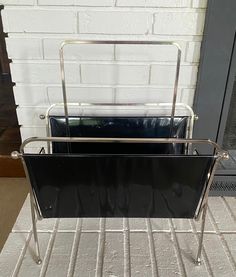 a black and silver metal basket sitting on top of a white tile floor next to a fireplace