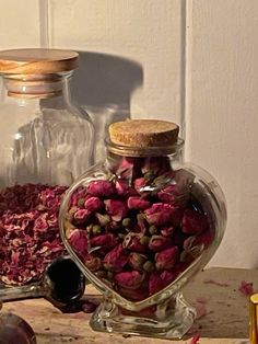 two glass jars filled with dried flowers on top of a wooden table next to other items