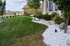 a yard with rocks and grass next to a house