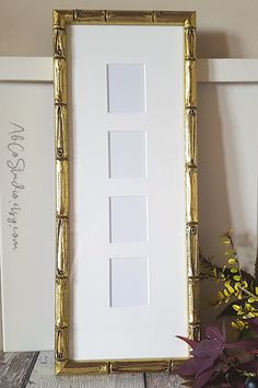 a white and gold frame sitting on top of a table next to a potted plant