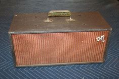 an old brown amp sitting on top of a blue carpeted floor next to a wall