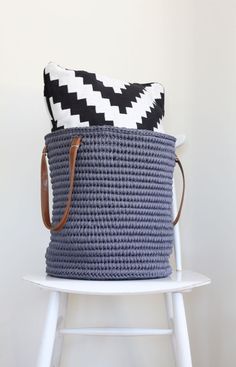 a blue and white basket sitting on top of a chair next to a black and white pillow