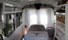 the inside of an rv with a bed and shelves on each side, windows open to let in light