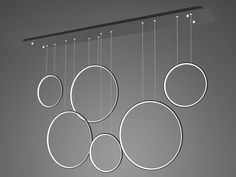 a group of circular lights hanging from the ceiling in front of a gray wall with circles on it