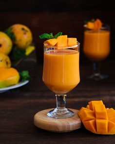 a glass filled with orange juice next to sliced mangoes