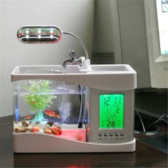 a clock that is on top of a desk next to a fish tank and computer