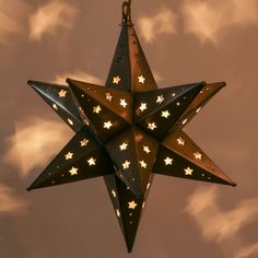 a lighted star hanging from the ceiling in front of cloudy sky with stars on it