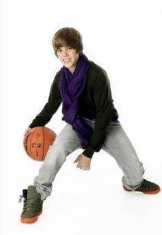 a young man is holding a basketball and posing for the camera with his hands on his hips