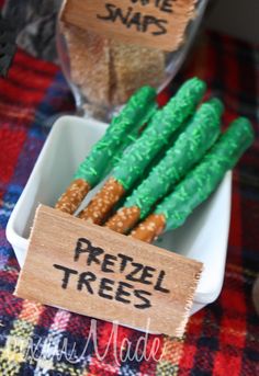 some pretzel trees are in a white bowl on a plaid tablecloth and there is a sign that says pretzel trees