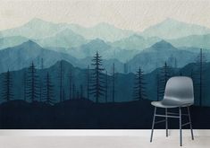 a chair sitting in front of a wall mural with mountains and trees painted on it