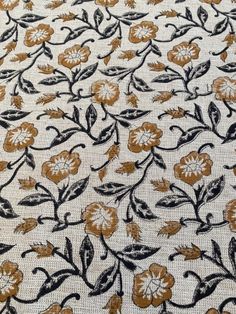 an embroidered fabric with gold and black flowers on white background, closeup view from the bottom