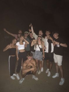 a group of people standing next to each other posing for a photo at night time