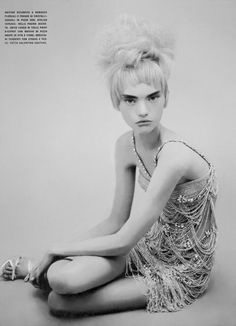 a woman sitting on the ground with her legs crossed in front of her face and hair pulled back