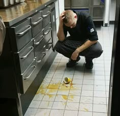 a man kneeling down on the floor in front of a kitchen counter with yellow stains all over it