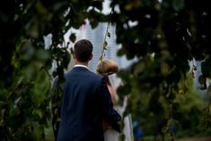 a bride and groom walking through the trees at their wedding ceremony in front of skyscrapers