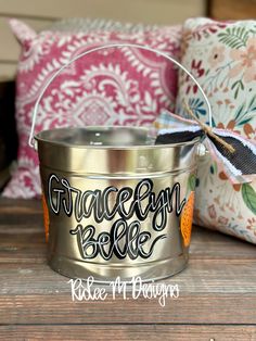 a metal bucket with the words grace and bliss painted on it sitting on a wooden table