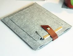 an ipad case sitting on top of a white table next to a cup and pen