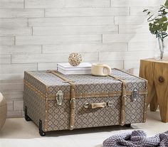 an old suitcase is sitting on the floor in front of a white brick wall and table