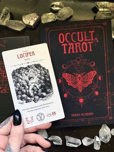 a person holding up a card next to an oraclel tarot book on a table