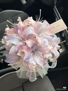 a bouquet of pink flowers sitting in the passenger seat of a car with a note attached to it