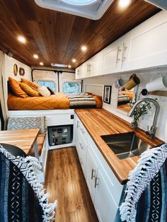 the interior of a camper with wood flooring and white cabinets, including a sink