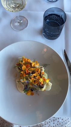 a white plate topped with food on top of a table next to glasses and utensils