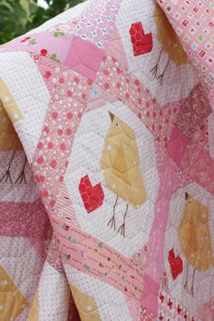 a pink quilt with yellow and red birds on it