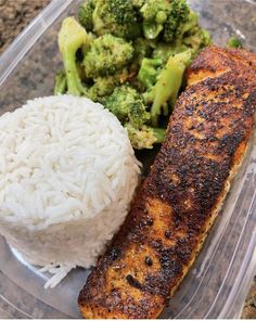 a plastic container with rice, broccoli and salmon