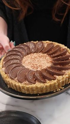 a person holding a chocolate pie on a plate