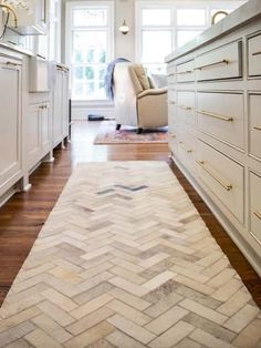 a white kitchen with herringbone rug on the floor