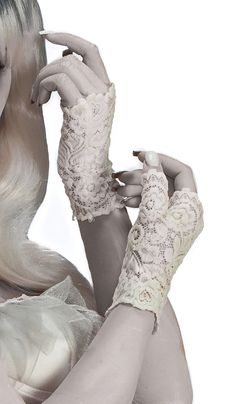 a woman with long white hair and gloves on her hands is posing for the camera