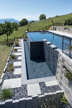 an outdoor swimming pool in the middle of a grassy area with steps leading up to it