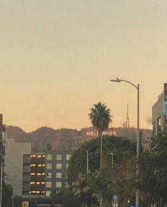 a city street filled with traffic next to tall buildings and palm trees in the background