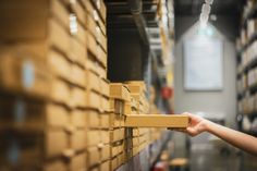 a person is reaching for boxes in a large storage room with shelves full of boxes