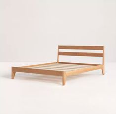 a wooden bed frame sitting on top of a white floor next to an empty wall