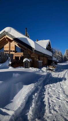 the house is covered in snow and it's surrounded by trees