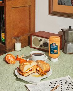 a sandwich cut in half sitting on top of a table next to a cup of coffee