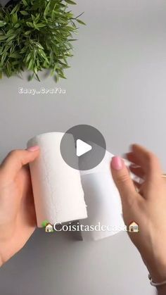 someone is holding a roll of toilet paper in front of a plant on the wall